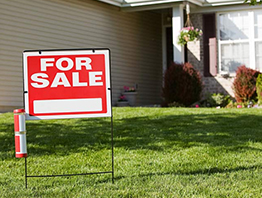 A 'Home For Sale' board displayed in front of a house, indicating it is on the market