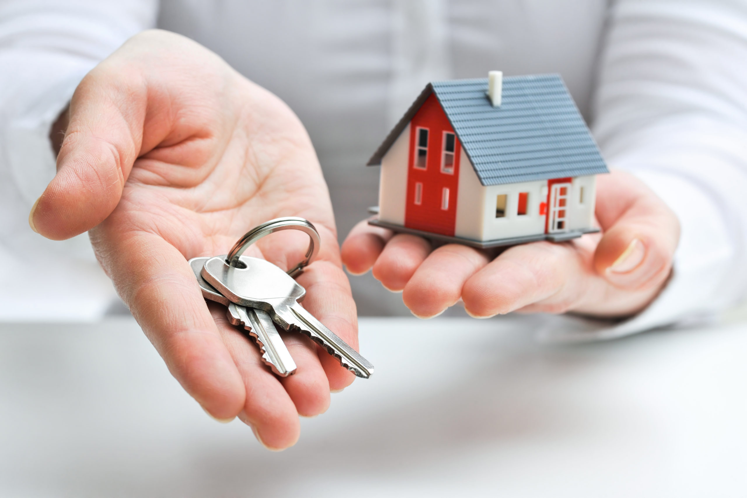 Hands holding a small home and key